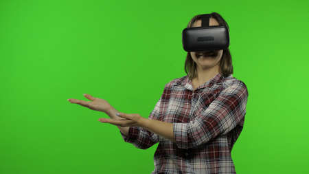 Young woman using VR headset helmet to play game, showing side advertising area. Pointing at blank...