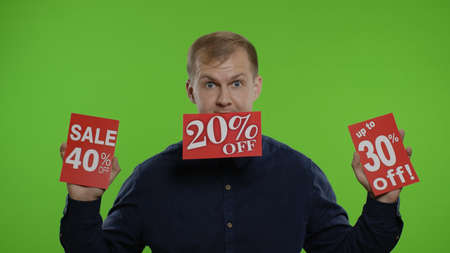 Excited happy emotions of store man client, smiling guy raising and showing sale purchase discounts advertisement inscriptions, looking satisfied with low prices. Chroma key backgroundの写真素材