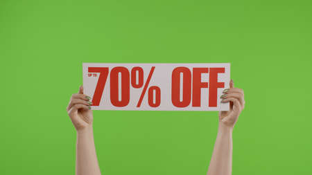 70 Percent Off advertisement inscription on paper sheet in womans hands on green screen. Holiday discounts, shopping with low cost purchase on Black Friday. Chroma key background. 6k downscaleの写真素材