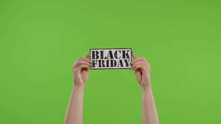 Black Friday advertisement inscription on paper sheet in womans hands on green screen. Holiday discounts, shopping with low cost purchase on big sale day. Chroma key background. 6k downscaleの写真素材