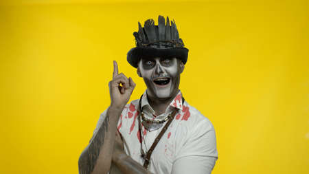 Creepy man with skeleton makeup in top-hat with feathers. Clever guy considering serious plan,...