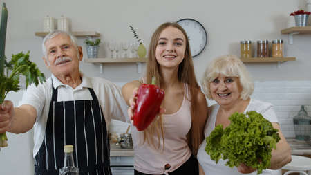 Senior grandparents couple with granddaughter in kitchen. Girl with mature man and woman...