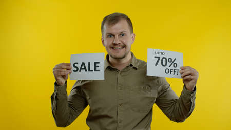 Great discounts. Happy cheerful blonde man showing Sale word and showing Up To 70 percent Off...