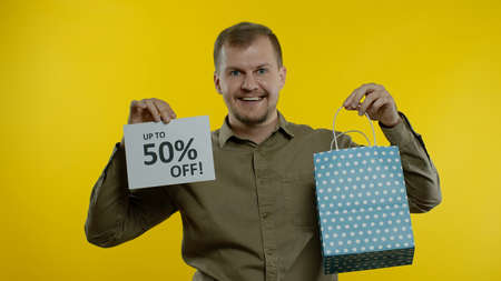 Happy man showing shopping bag and Up To 50 percent Off inscription note, smiling, celebrating,...