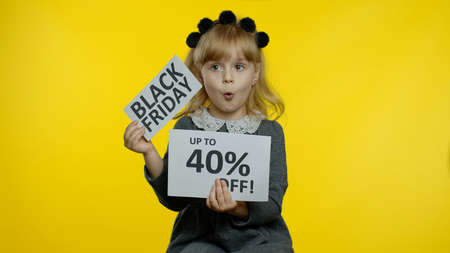 Excited child girl in school uniform showing Black Friday and Up To 40 Percent Off discount advertisement inscriptions banners. Kid rejoicing good discounts, low prices for online shopping salesの写真素材