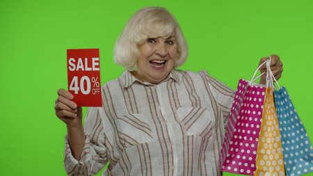 Cheerful grandmother with shopping bags showing Sale 40 percent Off banner text advertisement....