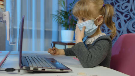 Preschool child girl distance online learning at home. Cute kid pupil studying with teacher using...