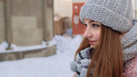 Close-up of young tourist woman warming her cold hands outdoors in winter day. Portrait of Caucasian...