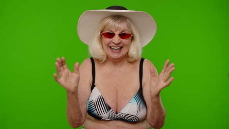 Senior woman tourist raising hand in victorious gesture, dancing, celebrating success, enjoying luck