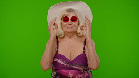 Elderly woman tourist in swimsuit relaxing, meditating, practicing yoga, calms down on chroma key