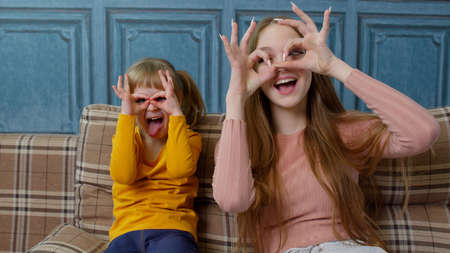 Funny young mother and daughter making funny faces taking selfie at home enjoying funny activityの写真素材