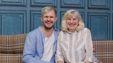 Happy bonding loving generations family of senior mother and handsome adult son or grandson laughing