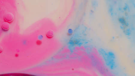 Top view movement of bright oil bubbles in slow motion. Multicolored surface background. Fantastic universe structure of colorful moving pink bubbles. Artistic image of ink drops floating on waterの写真素材