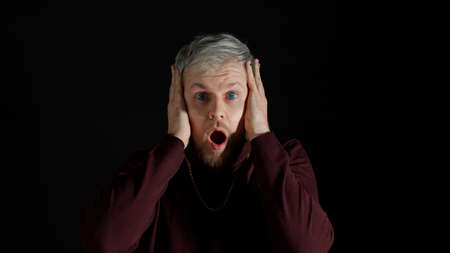 Shocked amazed handsome man in stylish blouse feeling excitement, looking at camera and holding...
