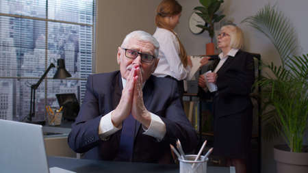 Elderly man boss pleading expression, begging apology, beseeching with hopeful face in office....
