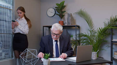 Focused business man entrepreneur typing on laptop doing research. Senior professional using computer sitting at office desk. Busy worker freelancer working on modern tech notebook device. Coworking.の写真素材
