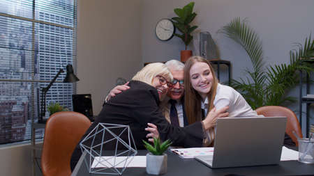 Diverse motivated business people rejoicing developing of business project. Company collegues making huggings celebrating corporate unity success good results reward at officeの写真素材