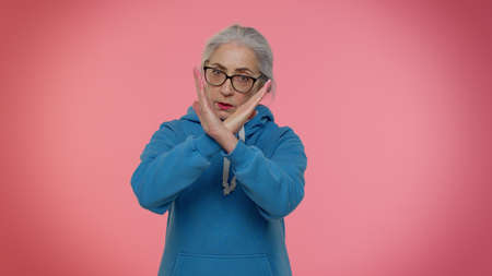 Elderly granny gray-haired woman say no hold palm folded crossed hands in stop gesture, warning of finish, prohibited access, declining communication, body language, danger. Senior old grandmotherの写真素材