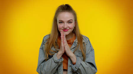 Villain idea. Sneaky teen student girl conspiring scheming, thinking over tricky plan with cunning expression, pondering revenge or evil joke prank. Young woman isolated on yellow wall backgroundの写真素材