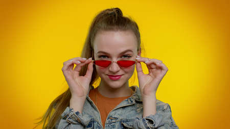 Close-up shot seductive cheerful teen stylish girl in denim jacket wearing sunglasses, charming...