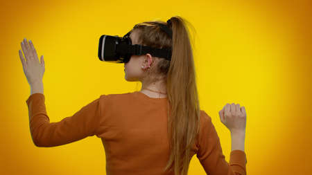 Rear view of amazed teen student girl using headset helmet app play simulation game. Watching...