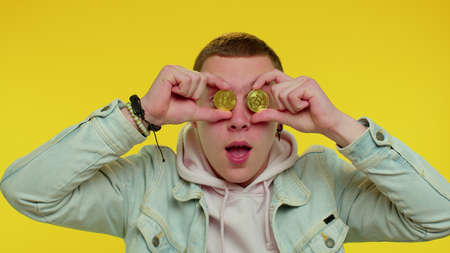 Handsome rich stylish teen boy showing golden bitcoins. Achievement career wealth, cryptocurrency...