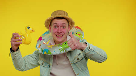 Traveler tourist teen student boy dancing fooling with swimming ring and inflatable duck toy, travel...