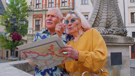 Senior couple grandmother and grandfather tourists in stylish clothing looking for a place to go in...