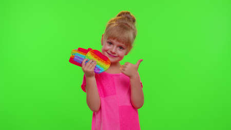 Smiling child girl kid holding squeezing anti-stress toys simple dimple game. Children playing popular pop up touch screen game with buttons.の写真素材