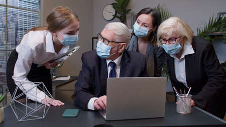 Group business people have a meeting and working with laptop computer in office and wear masks as...