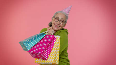 Elderly granny stylish woman showing shopping bags, advertising discounts, smiling looking amazed...