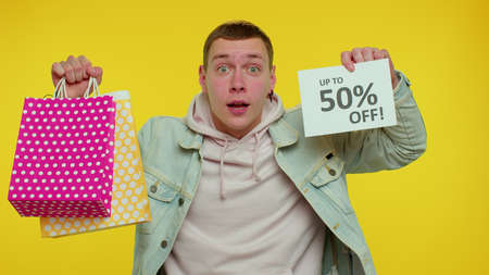 Cheerful teenager boy showing shopping bags and Up To 50 Percent Off inscriptions banner text. Black...