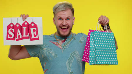 Happy adult man showing Sale inscription banner text, advertising discounts, smiling looking amazed...
