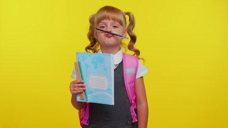 Funny joyful kid primary school girl with ponytails wearing uniform making playful silly facial...