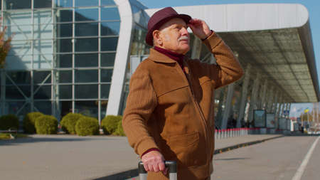 Portrait of elderly retired man tourist near airport terminal waiting boarding on plane for...
