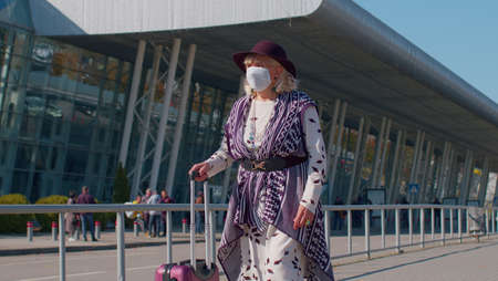 Portrait one unhappy old senior woman grandmother businesswoman wearing Protective Face Mask COVID-19 coronavirus infection near airport pandemic disease virus tourist, epidemic illness, slow motion.の写真素材
