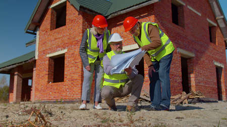 Diverse team of specialists taking near modern house. Real estate building project with senior civil...