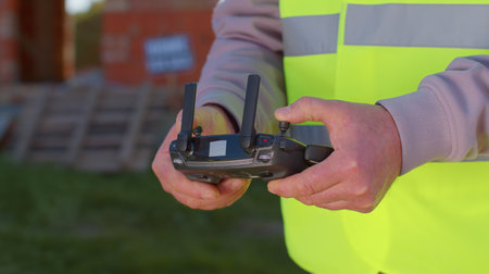 Drone operator controls an aircraft, hands holding remote controller close-up. Professional builder...