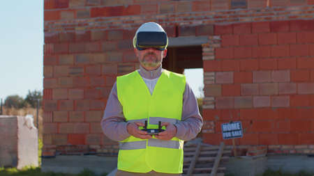 Drone operator controls an aircraft, holding remote controller. Professional builder in virtual...