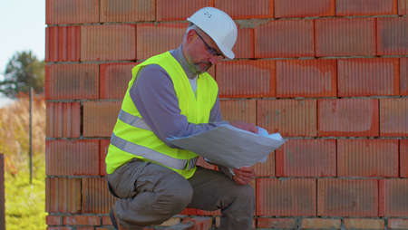 Confident engineer architect wearing a safety hardhat and vest working repairing on construction...
