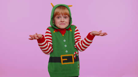 I dont know what to say. Confused one girl in Christmas Santa helper Elf costume feeling embarrassed about ambiguous question, having doubts, no idea, being clueless and uncertain on violet backgroundの写真素材