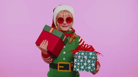 Girl toddler Christmas Santa Claus helper Elf holds two gifts in hands and does not know which one...