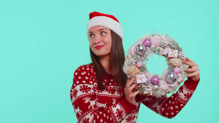 Portrait of fun adult girl 20s in red Christmas deer sweater look camera smiling hold raise point...