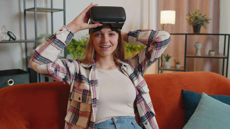 Young woman use VR headset glasses at home, enjoying 3D 360 video concept, entertaining, in positive...