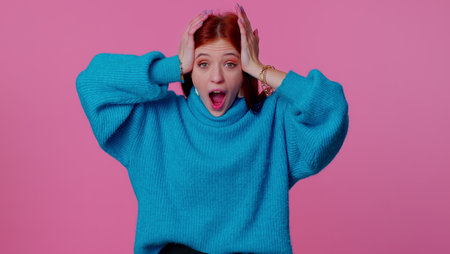 Oh my god wow. Excited amazed teen student girl 20s raising hands in surprise looking at camera with...