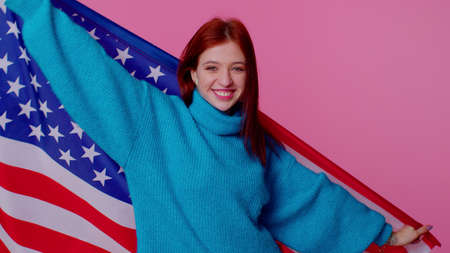 Trendy cheerful positive teen girl waving and wrapping in American USA flag, celebrating, human...