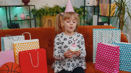 Young little children girl sitting on sofa with lots of gift presents, celebrating birthday party...