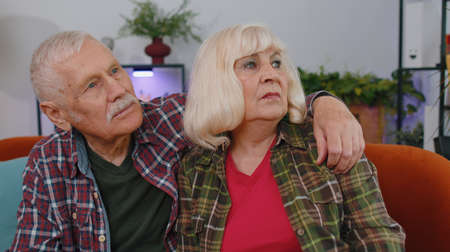 Close-up sad senior elderly family grandparents man woman sitting at home thinks over lonely life or...