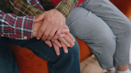 Close up of caring elderly grandmother wife holding hands supporting senior grandfather husband give empathy care love, old married grandparents couple together two man and woman hope understandingの写真素材