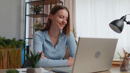 Young woman freelancer sitting at home office desk making video call chat conversation conference...